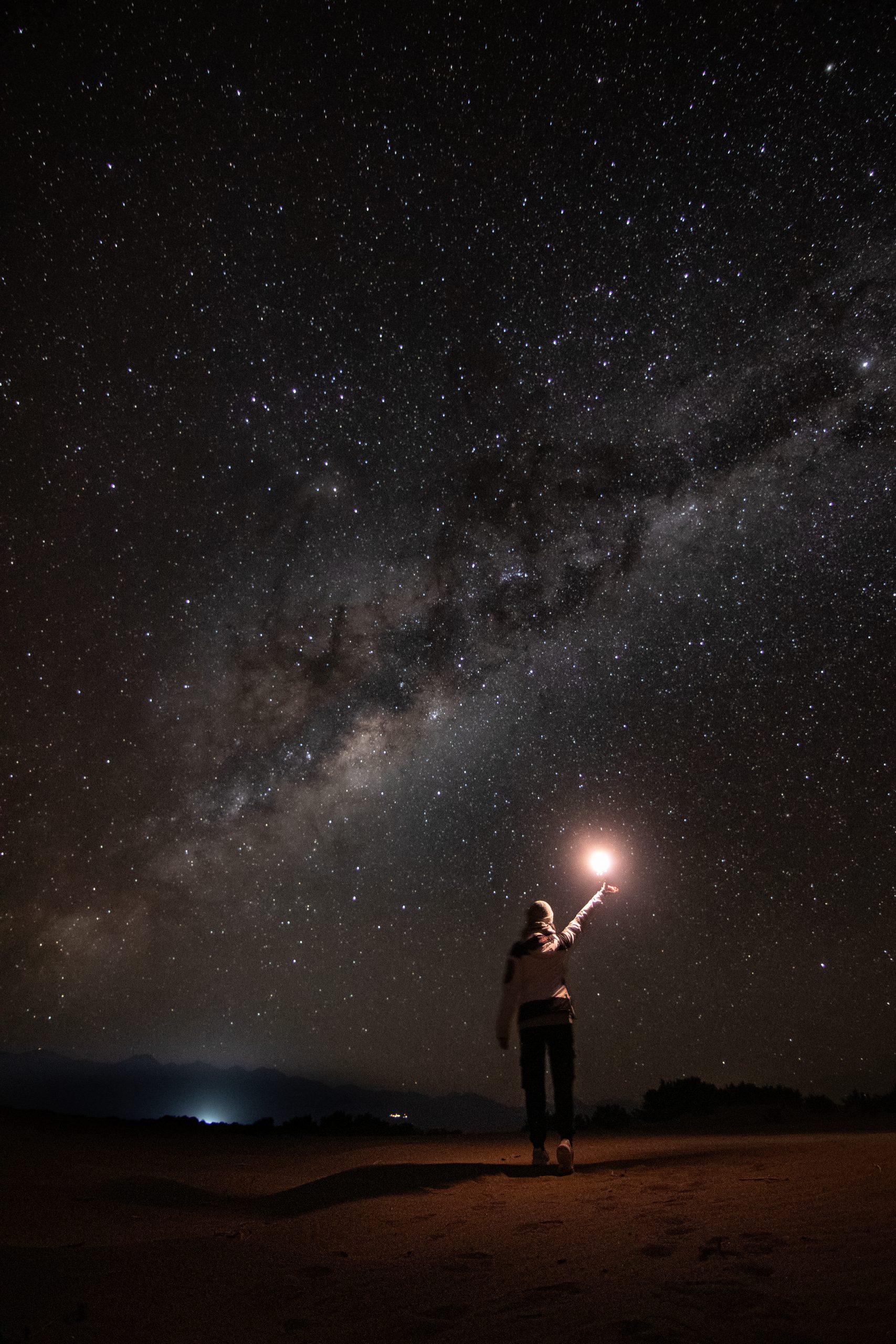 Foto de mujer sosteniendo una luz caminando hacia la vía láctea 