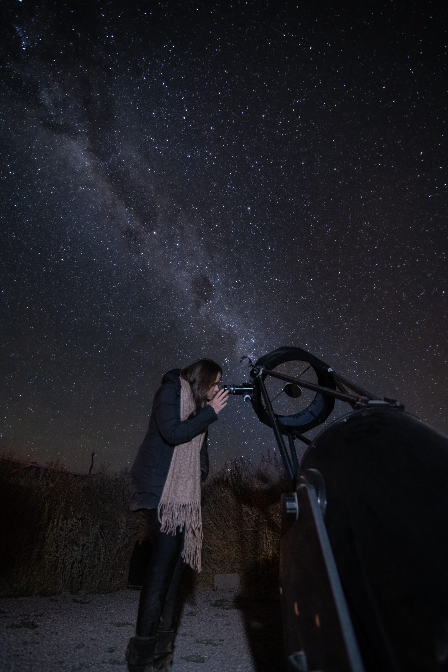 Mujer observando hacia las estrellas con un telescopio