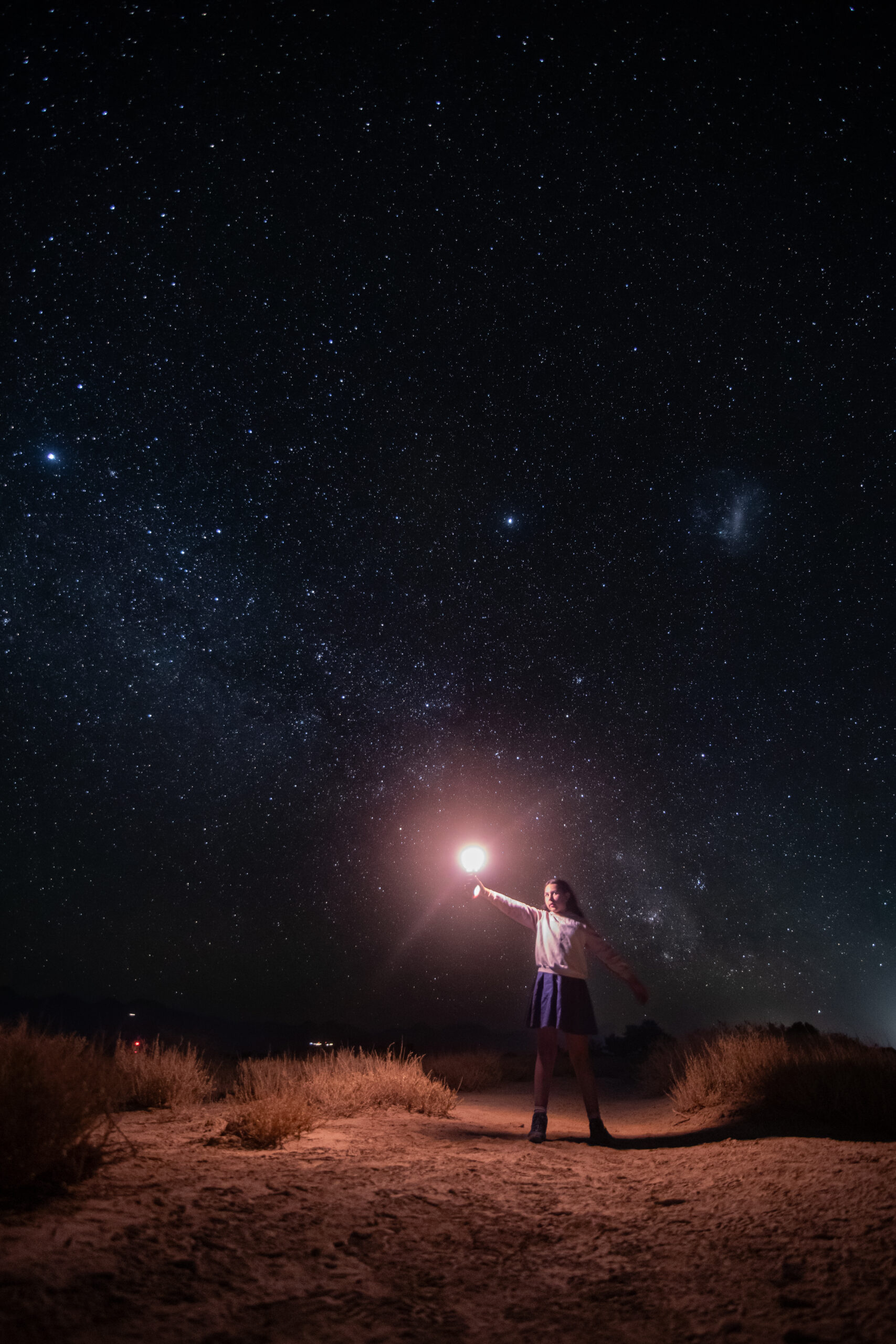 Niña sosteniendo una luz hacia el cielo estrellado